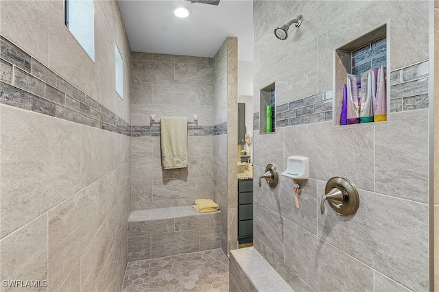 bathroom with tile walls, tiled shower, and vanity