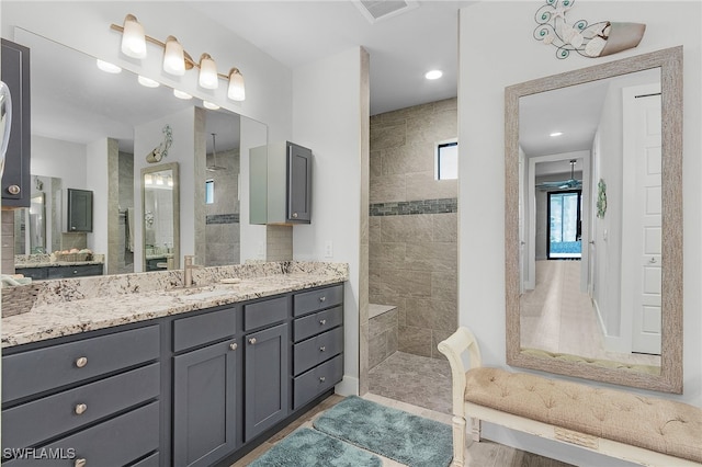 bathroom featuring vanity, hardwood / wood-style flooring, and tiled shower