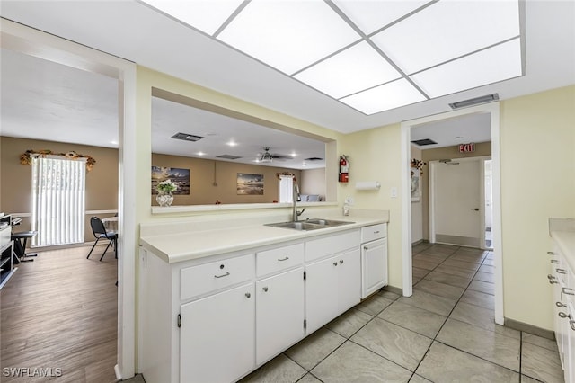 kitchen with white cabinets, ceiling fan, sink, and light hardwood / wood-style flooring