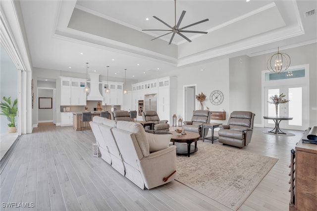 living room with crown molding, a raised ceiling, and light hardwood / wood-style flooring