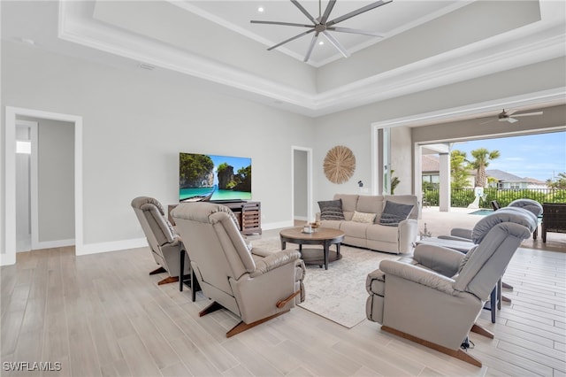 living room featuring light hardwood / wood-style floors, a raised ceiling, a high ceiling, and ceiling fan