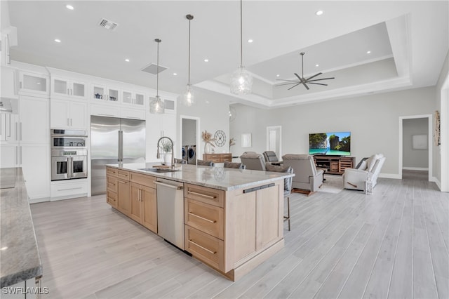 kitchen with a large island, sink, white cabinets, light brown cabinetry, and appliances with stainless steel finishes