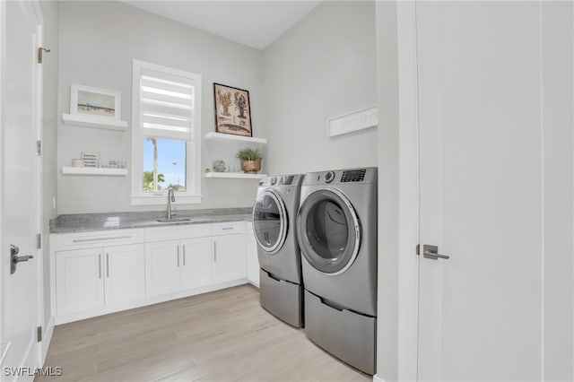 laundry area featuring light hardwood / wood-style floors, sink, cabinets, and washing machine and dryer