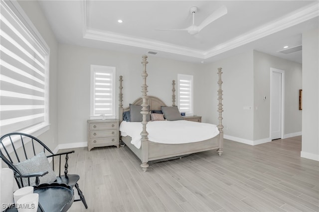 bedroom featuring light hardwood / wood-style flooring, multiple windows, and a raised ceiling