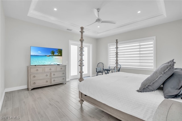 bedroom with a tray ceiling, light hardwood / wood-style floors, and ceiling fan