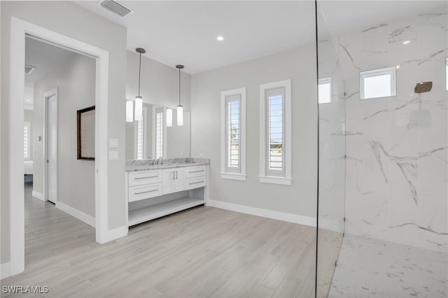 bathroom with vanity, hardwood / wood-style flooring, and a tile shower