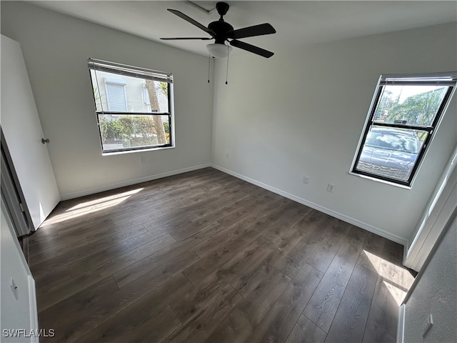 spare room with ceiling fan, a wealth of natural light, and dark hardwood / wood-style flooring