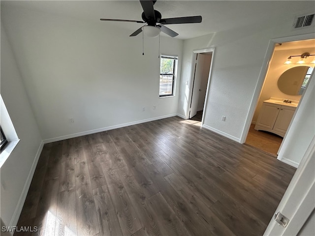 unfurnished bedroom with dark wood-type flooring, ensuite bath, and ceiling fan