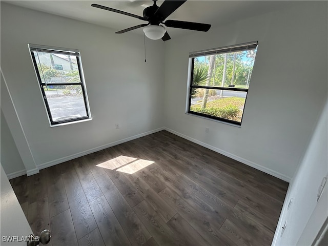 empty room featuring a wealth of natural light, dark wood-type flooring, and ceiling fan