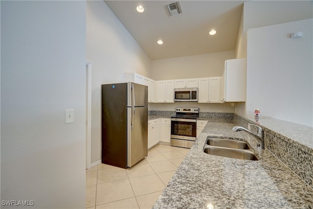 kitchen with appliances with stainless steel finishes, sink, high vaulted ceiling, white cabinets, and light tile patterned flooring