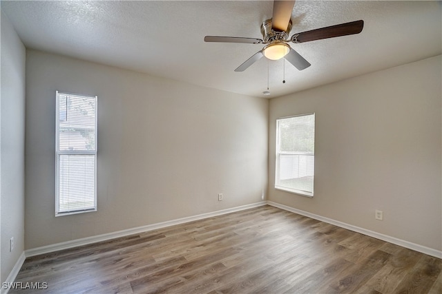 spare room featuring a wealth of natural light, ceiling fan, hardwood / wood-style flooring, and a textured ceiling