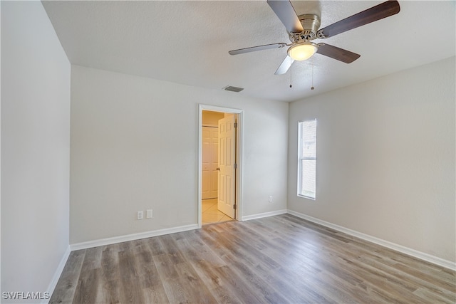 spare room featuring ceiling fan, light hardwood / wood-style flooring, and a textured ceiling