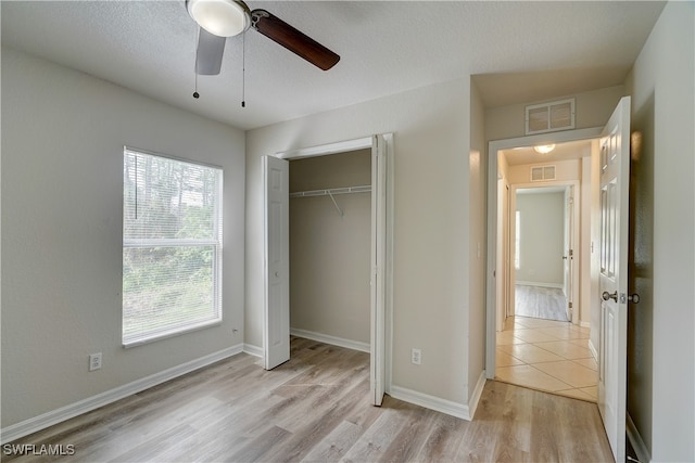 unfurnished bedroom featuring ceiling fan, a closet, a textured ceiling, and light wood-type flooring