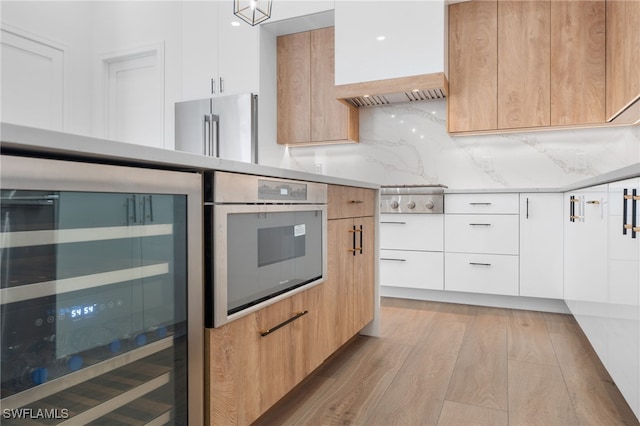 kitchen with white cabinetry, custom range hood, wine cooler, and light hardwood / wood-style flooring