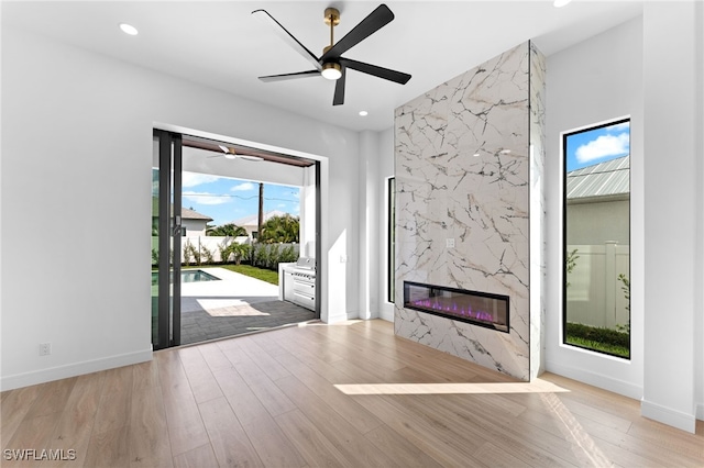 unfurnished living room featuring a high end fireplace, tile walls, and light wood-type flooring