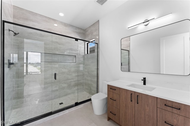 bathroom featuring vanity, toilet, and a shower with shower door