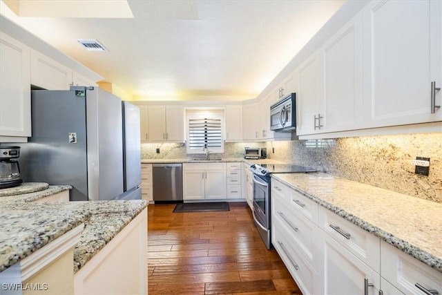 kitchen featuring light stone countertops, white cabinetry, sink, dark wood-type flooring, and appliances with stainless steel finishes