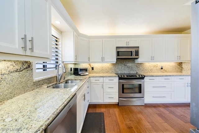 kitchen with decorative backsplash, stainless steel appliances, sink, light hardwood / wood-style floors, and white cabinetry