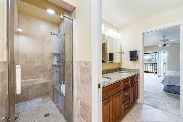 bathroom featuring ceiling fan, tile patterned floors, an enclosed shower, vanity, and tile walls