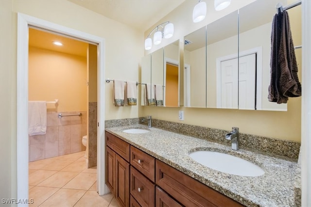 bathroom featuring tile patterned floors, vanity, toilet, and tile walls