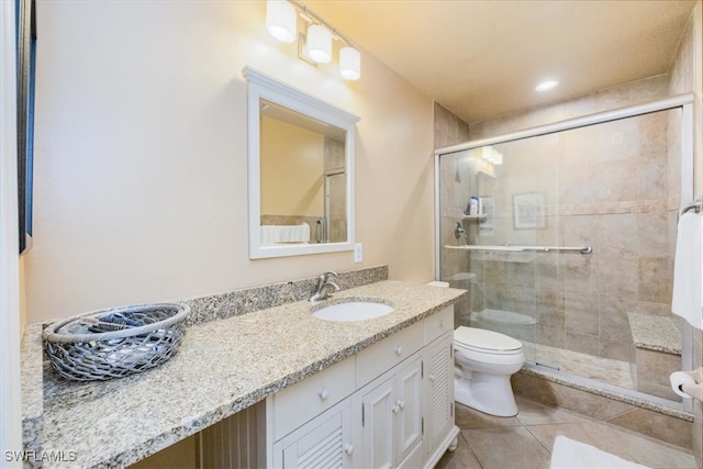 bathroom featuring tile patterned flooring, vanity, toilet, and a shower with door