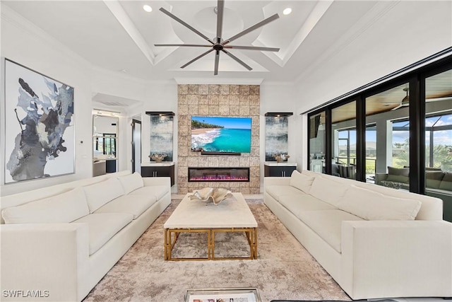 living room featuring a tiled fireplace, a wealth of natural light, built in shelves, and crown molding