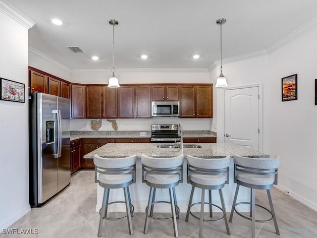 kitchen featuring ornamental molding, appliances with stainless steel finishes, hanging light fixtures, and an island with sink