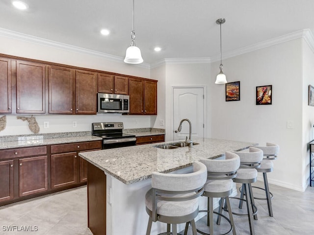 kitchen featuring sink, a kitchen bar, stainless steel appliances, ornamental molding, and a center island with sink