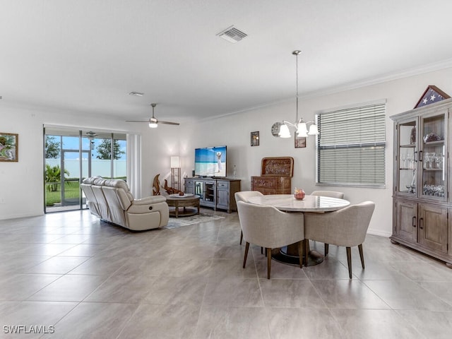 tiled dining area featuring crown molding and ceiling fan with notable chandelier