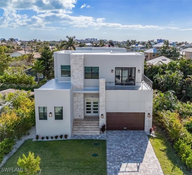 modern home with a front yard, a balcony, and a garage