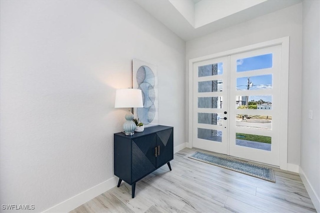 foyer featuring light wood-type flooring, french doors, and baseboards