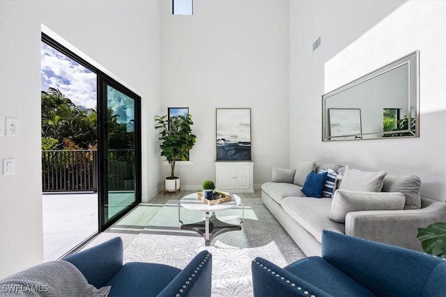 living room featuring a high ceiling, light hardwood / wood-style flooring, and a healthy amount of sunlight