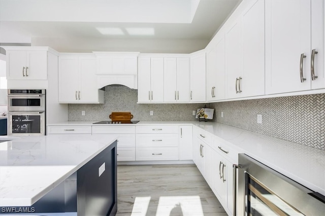 kitchen featuring wine cooler, backsplash, white cabinets, double oven, and black electric cooktop