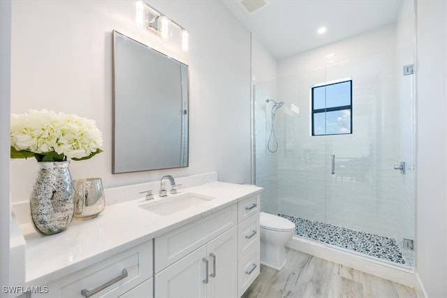 bathroom featuring toilet, walk in shower, hardwood / wood-style floors, and vanity