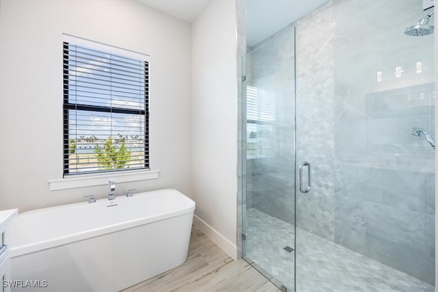 full bathroom featuring a stall shower, a soaking tub, wood finished floors, and baseboards