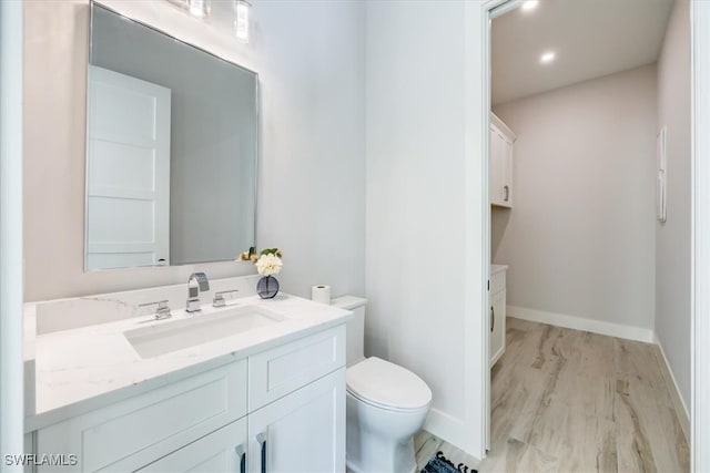 bathroom with toilet, baseboards, wood finished floors, and vanity