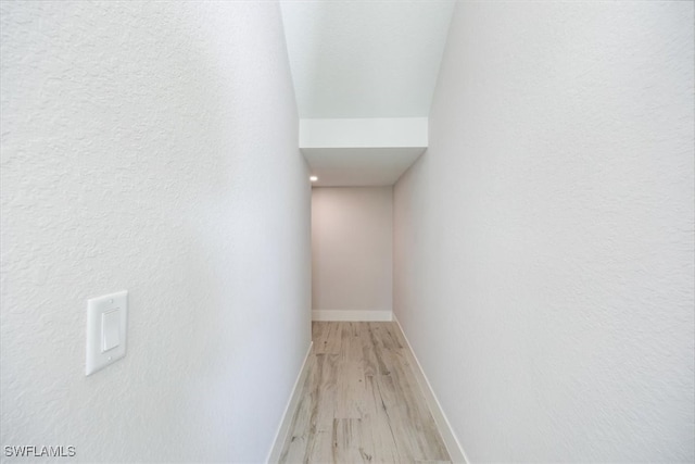 hall with light wood-style flooring and baseboards