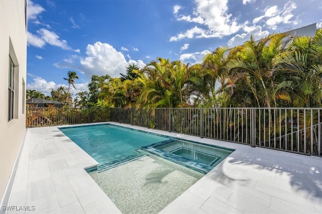 view of swimming pool with a pool with connected hot tub, a patio, and fence