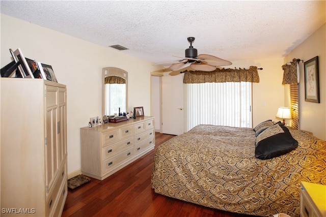 bedroom with ceiling fan, a textured ceiling, and dark hardwood / wood-style flooring