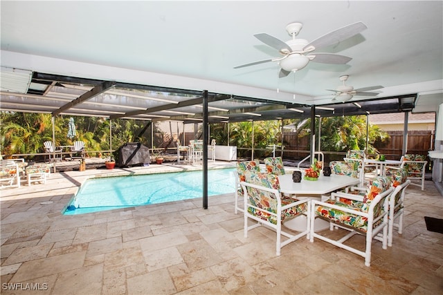 view of swimming pool with a patio area, glass enclosure, and ceiling fan