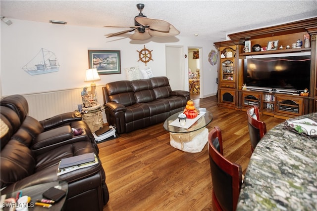 living room featuring ceiling fan, a textured ceiling, and hardwood / wood-style flooring