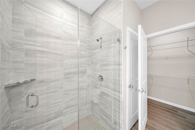 bathroom with a shower with shower door and hardwood / wood-style flooring