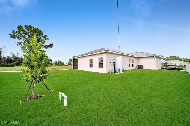 rear view of property with a lawn and central AC unit