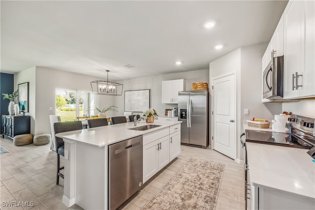 kitchen featuring white cabinetry, sink, stainless steel appliances, a breakfast bar area, and a center island with sink