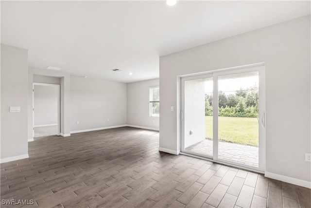 spare room with dark hardwood / wood-style flooring and a wealth of natural light