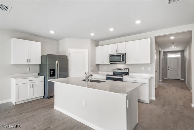 kitchen with sink, light hardwood / wood-style flooring, a kitchen island with sink, white cabinets, and appliances with stainless steel finishes