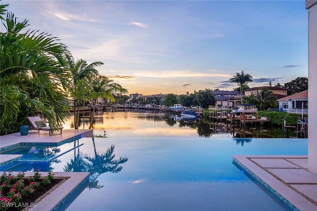 pool at dusk featuring a patio and a water view