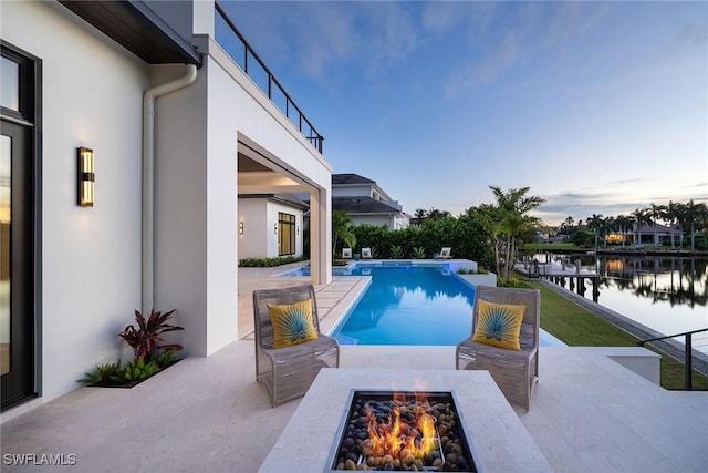 view of pool featuring a patio, a water view, and a fire pit