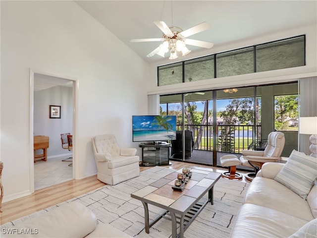 living room featuring light hardwood / wood-style flooring, high vaulted ceiling, and ceiling fan