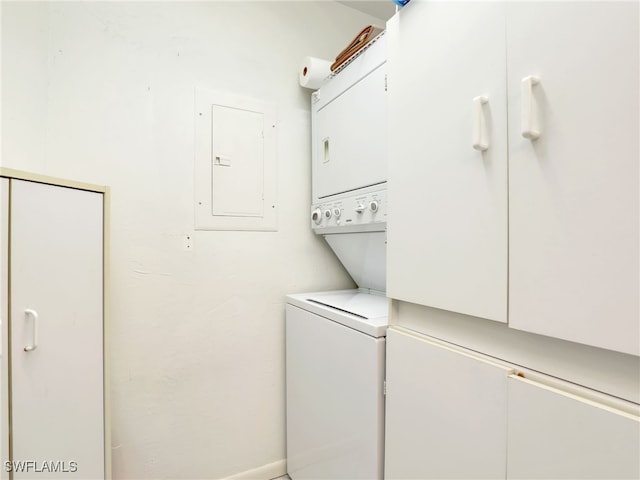 clothes washing area featuring electric panel and stacked washer / dryer